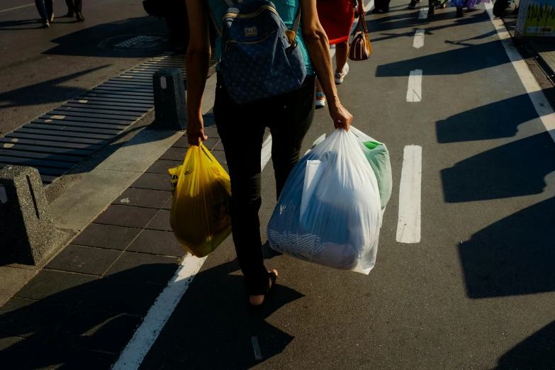 a woman carrying several bags walking down a street