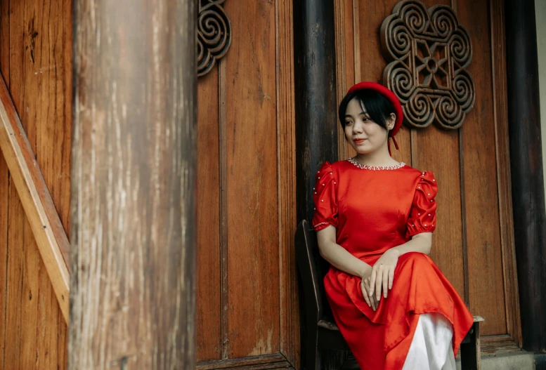 a woman in red sits on stairs looking at the camera