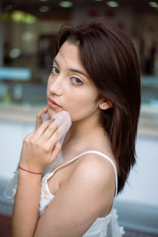 woman with large earrings and white tank top holding her nose