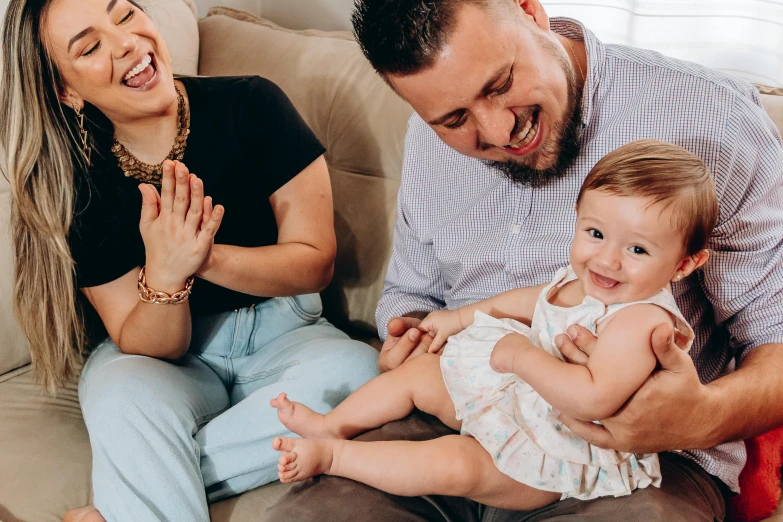 an adult and woman sitting on a couch with a baby