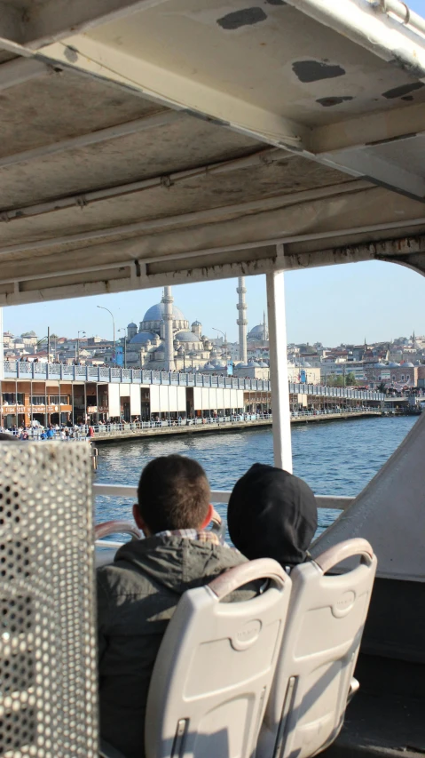 two people sitting on a boat watching soing out in the water