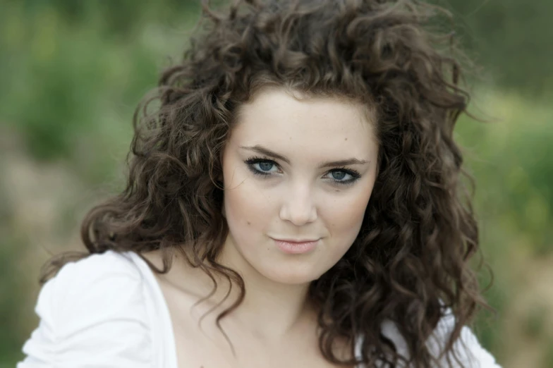 a woman with dark brown curly hair and blue eyes