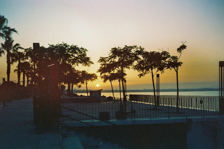 the setting sun at the beach as seen through a gate