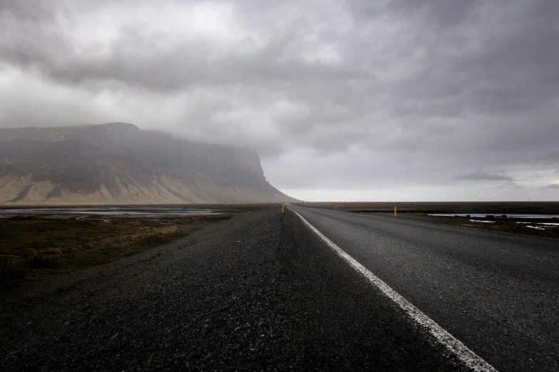 a lonely highway is shown under the cloudy sky