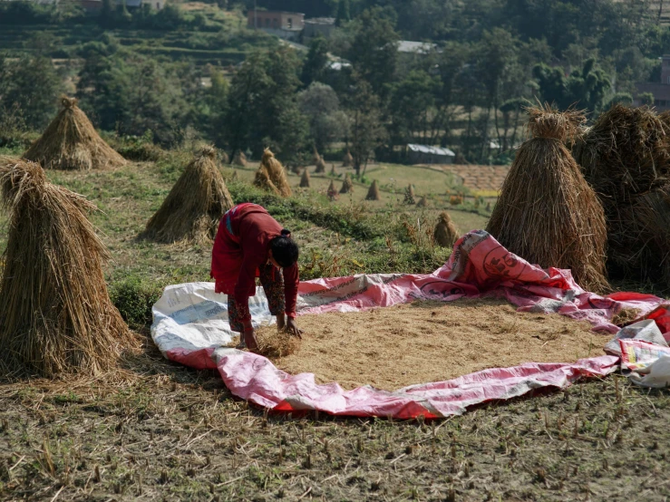 a woman standing on top of a field next to some hay