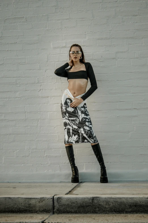 woman in black dress, skirt and boots on steps posing for the camera