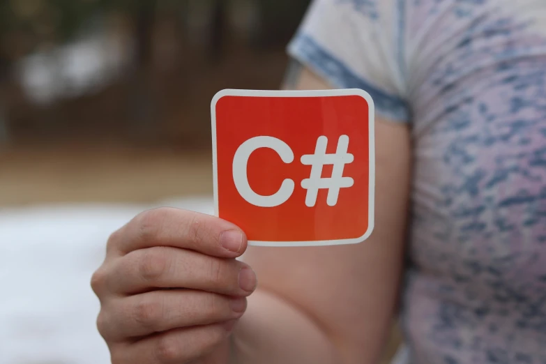 a person holding up an orange square sticker with the words c in it