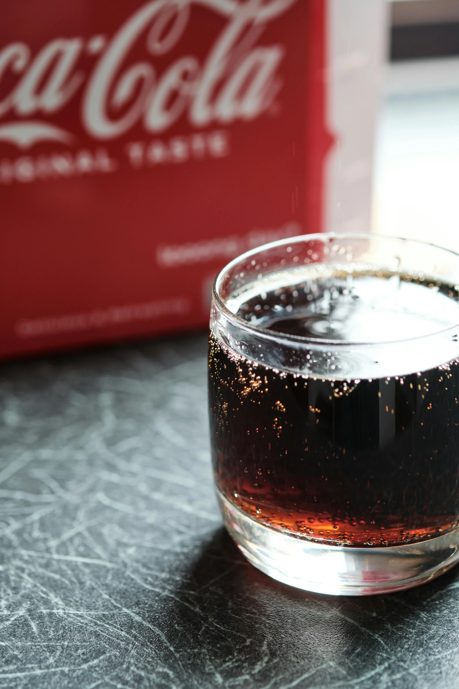 the soda is sitting in a glass cup on a table