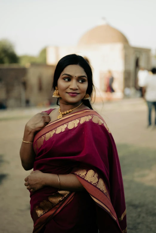 a woman standing outside, wearing a traditional indian outfit