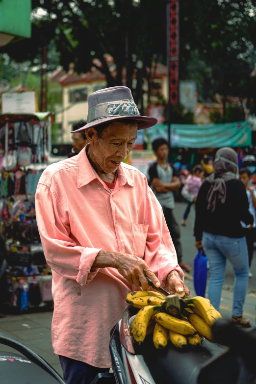 an older man picks up some bananas at a market