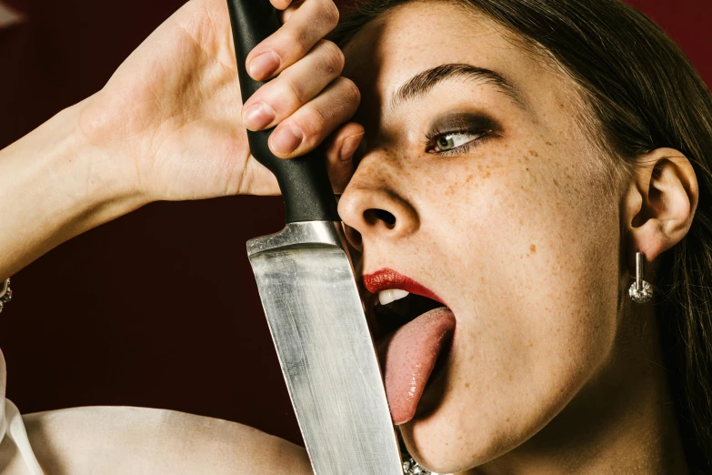 a close up of a woman making facial expression with a knife