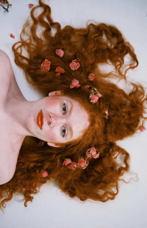 a very beautiful young redhead with red hair laying down