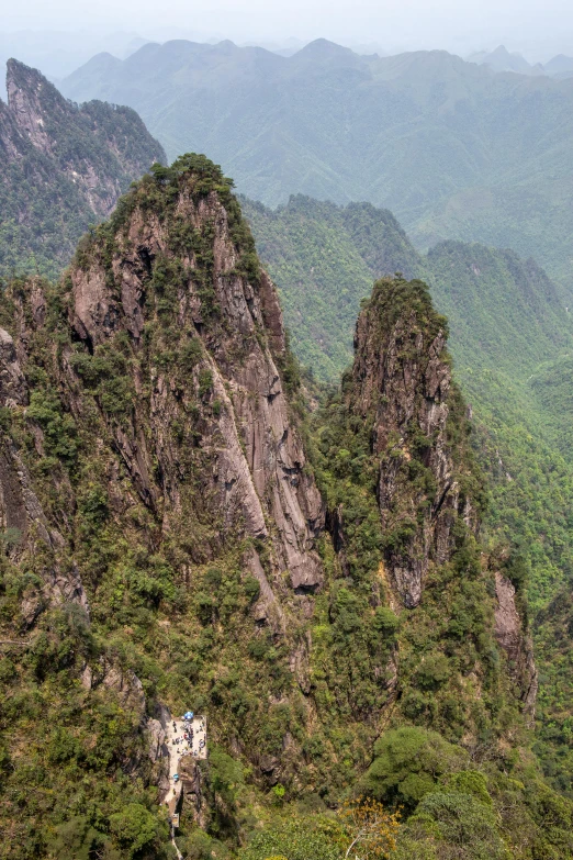 a man hiking in the jungle along side of mountains