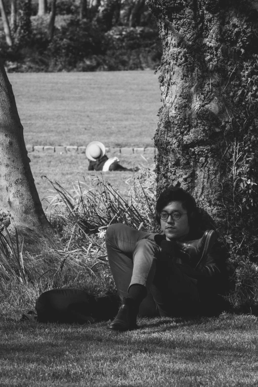 a woman sitting under a tree looking at the camera