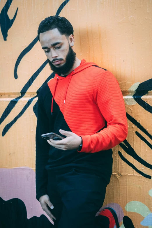 a young man in an orange sweatshirt using a cell phone