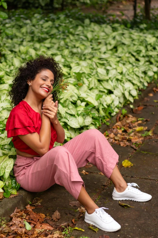 a woman sitting on the ground in front of many leafy plants