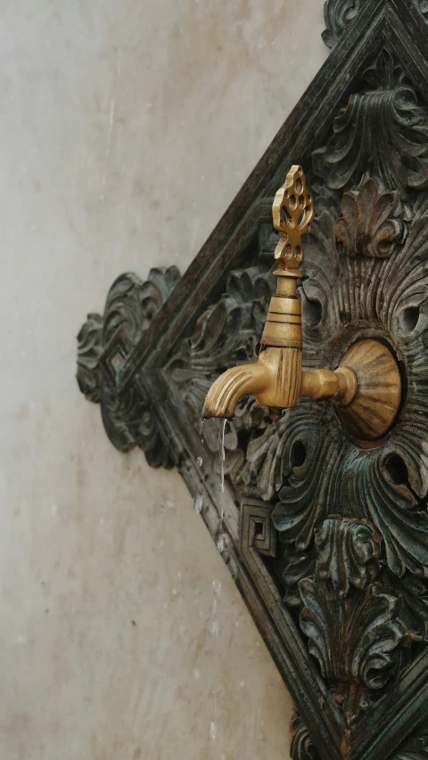 an intricately carved sculpture on the wall next to a water spout