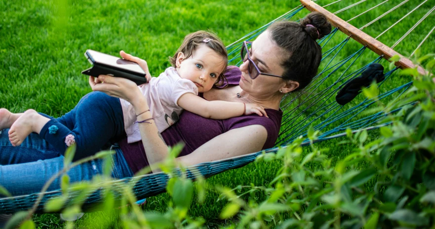 a woman and child sitting on a hammock reading