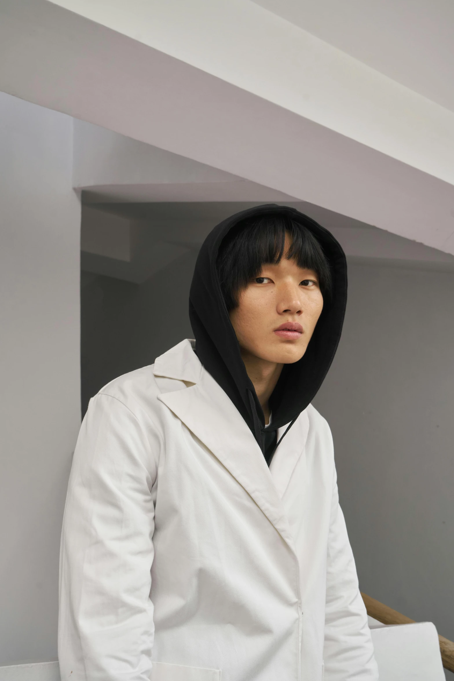 young man in white jacket leaning against a wall