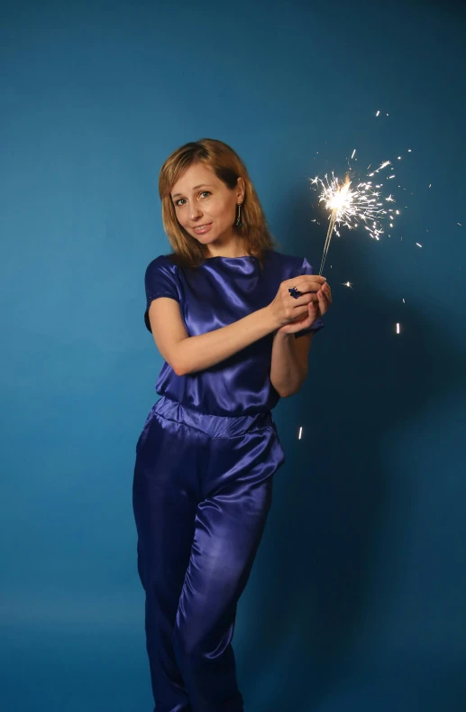 a woman in purple holding a sparkler up