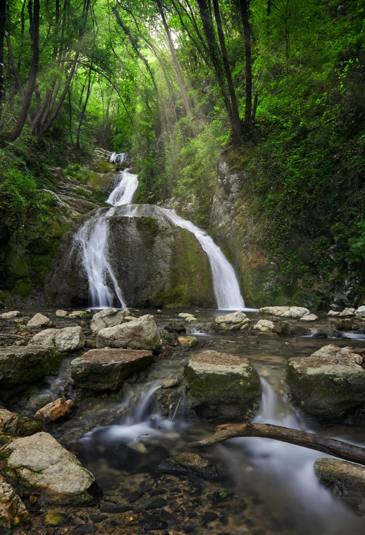 a waterfall is pouring from rocks through the forest