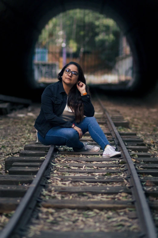 a young woman sits on a train track while holding an ice cream