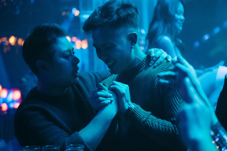 two people dance in a club or nightclub with their arms around one another