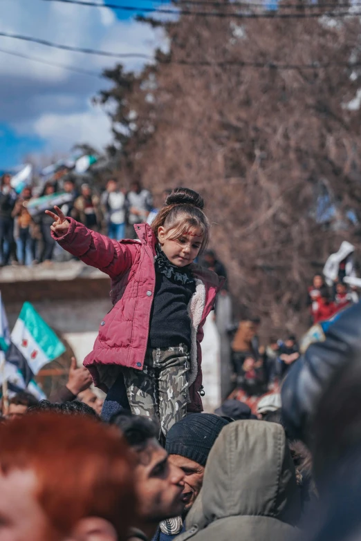 a small child stands on a railing with other people watching