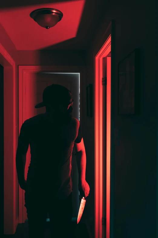 a man standing next to a hallway with a red light on it