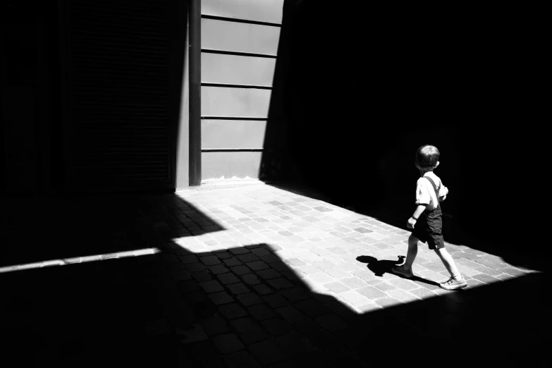 a small child walks through an alley with long shadows