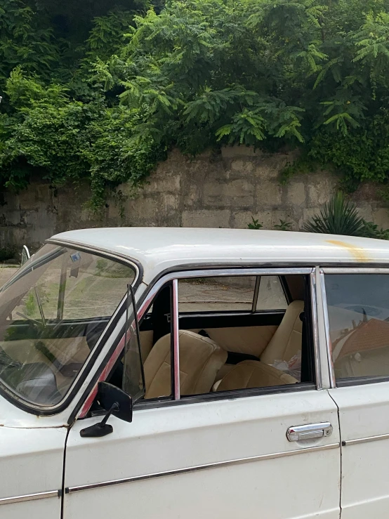 a white car parked next to a stone wall