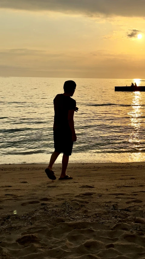 silhouettes of two people standing in front of the ocean