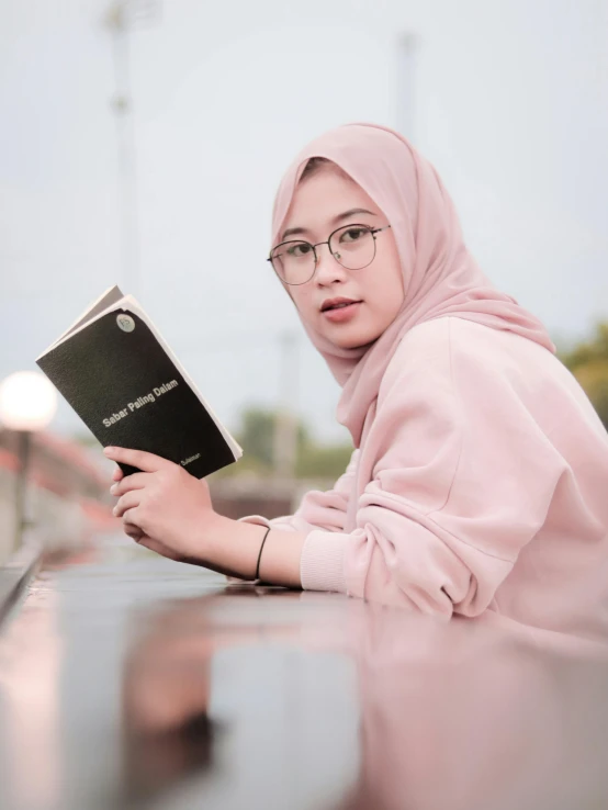 a young woman is sitting down reading a book