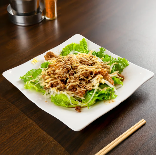 a white plate topped with salad and chopsticks