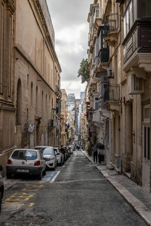 cars line the sides of a narrow city street