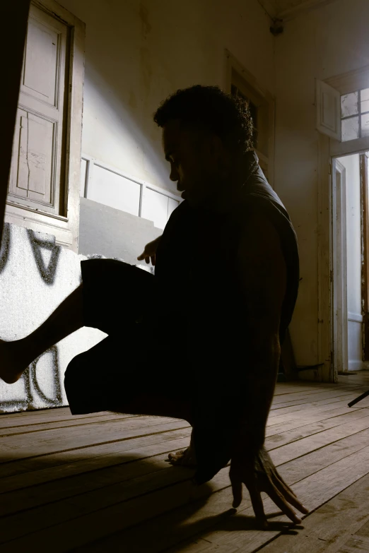 a man with arms stretched out crouching next to an open door