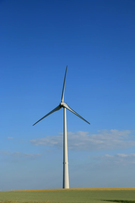 a wind turbine in a field with a clear blue sky