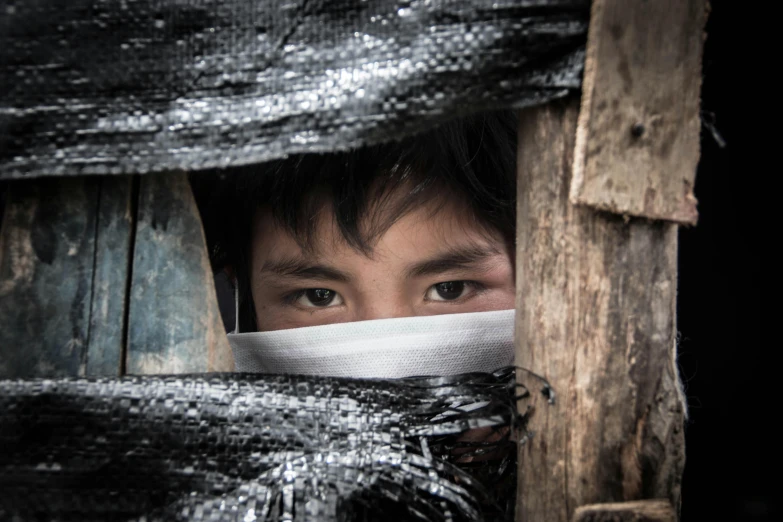 a man covering his face and peering through some duct tape