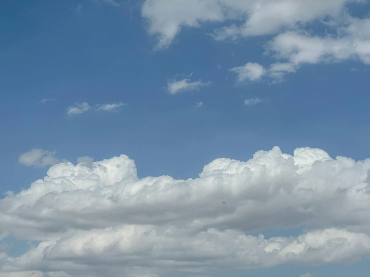 the plane is flying high in the sky with clouds