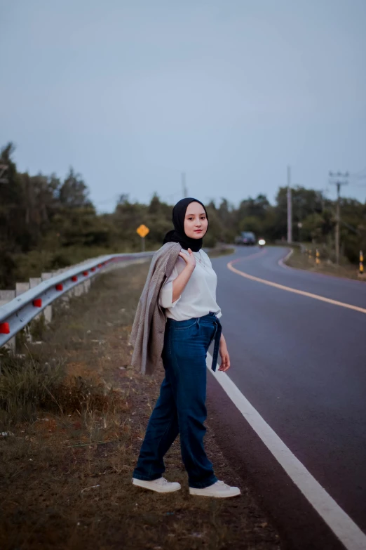 a woman poses for the camera on the side of a highway