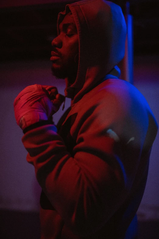 a man in a hoodie standing in the dark