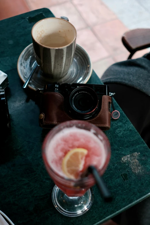 a red drink on top of a table near a camera