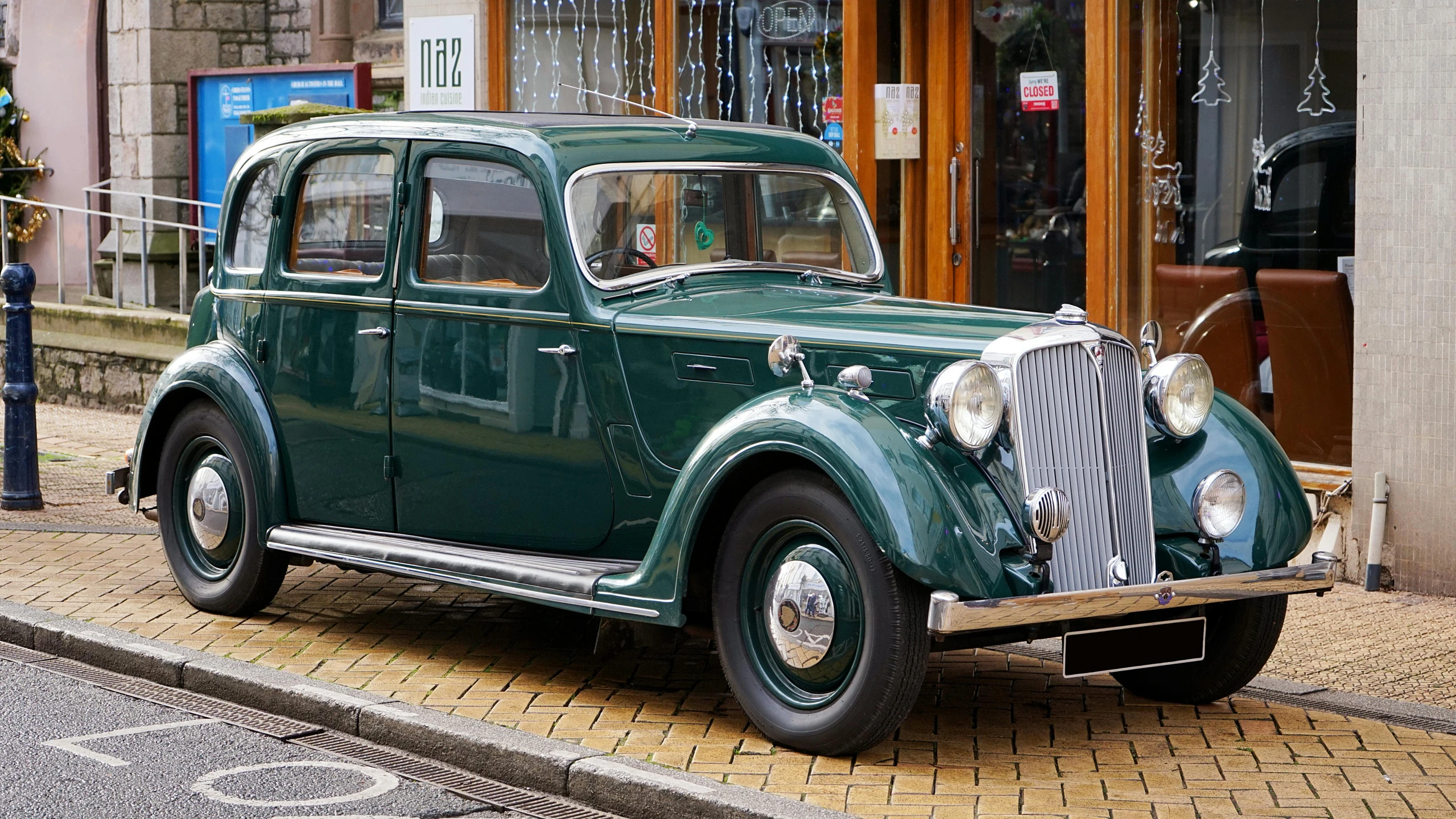 an old fashion green car parked on the side of a street