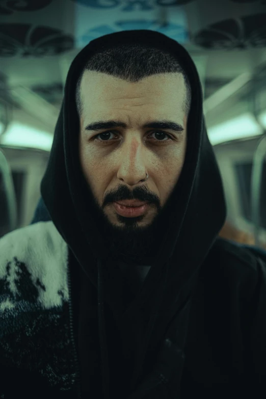 a man in a hoodie looking ahead while riding on a train