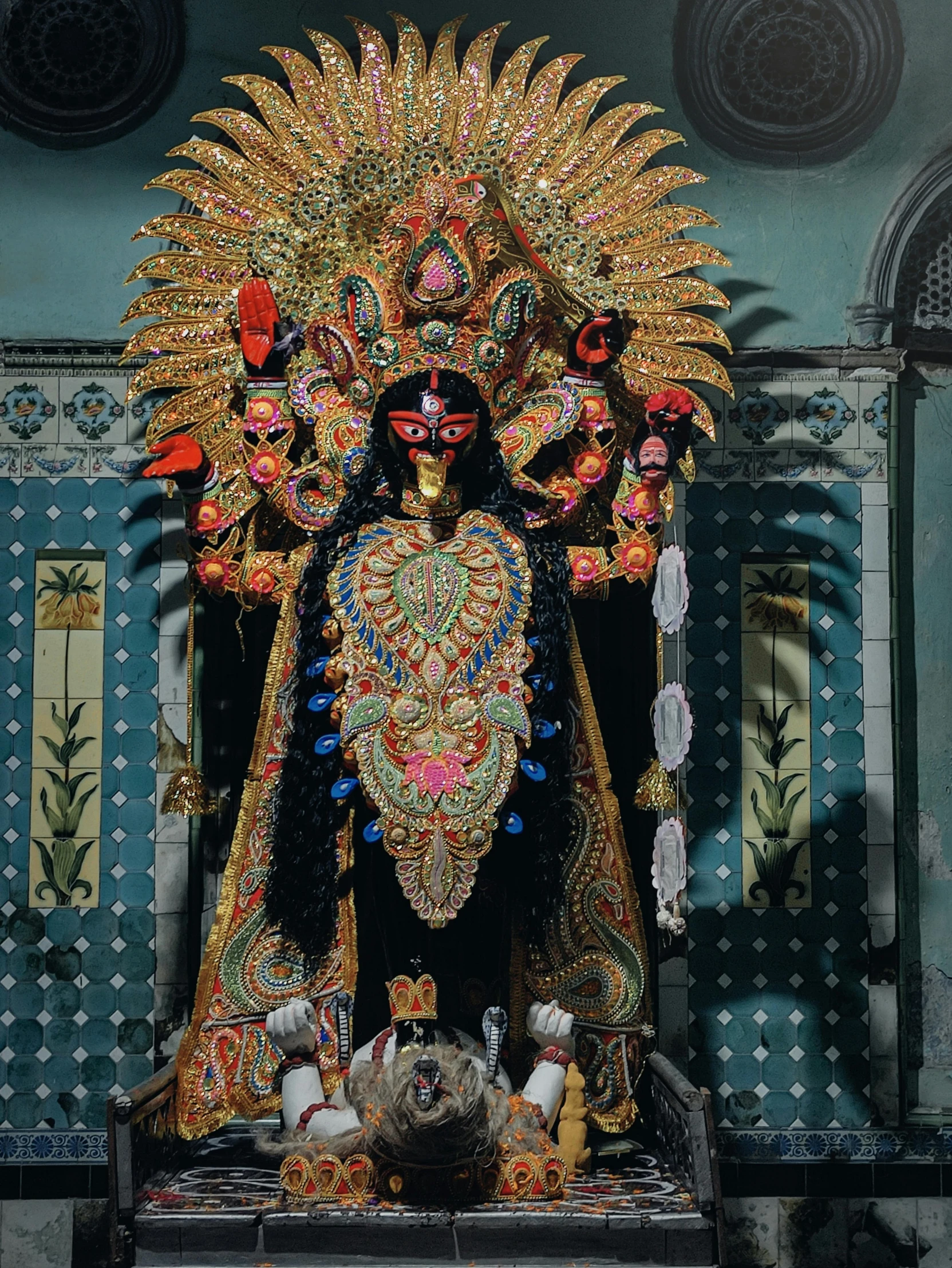 a statue with ornate decorations and feathers in front of a wall