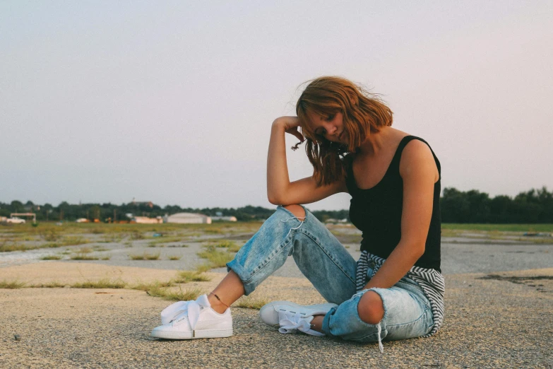 a woman sitting on the sand with her sneakers on