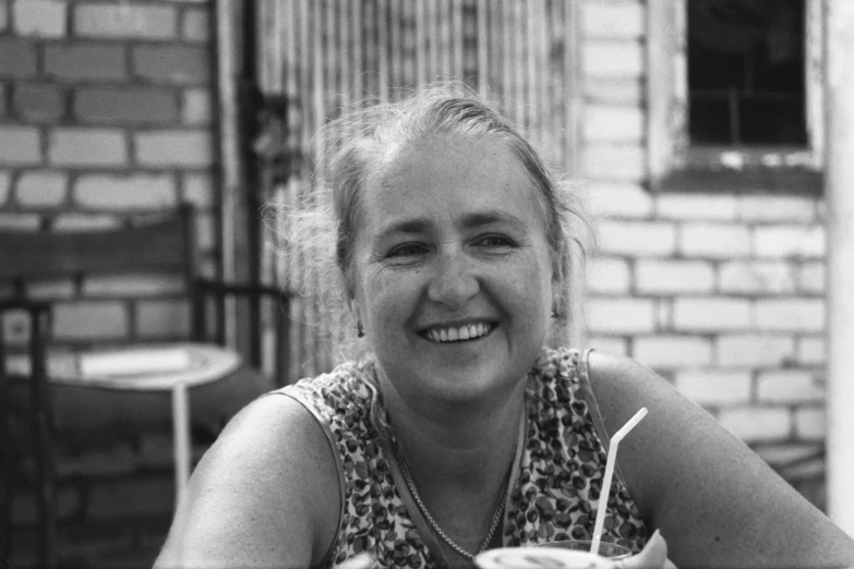 black and white pograph of a smiling woman sitting with her plate