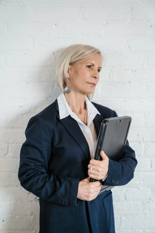 an older woman in suit and white shirt holds a binder