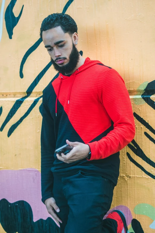 a man standing in front of graffiti holding his cellphone