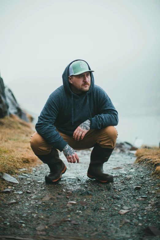 a person crouched on a trail near a body of water